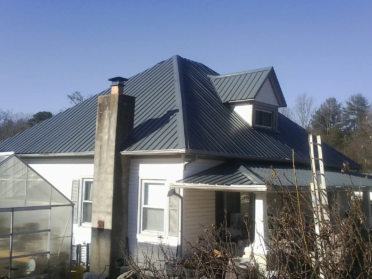 Dark blue standing seam metal roof on a white farmhouse with dormer — Slate & Tile Roof Repair by Roofing Brothers in Spangler