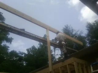 Carpenter setting a ridge beam over a new addition frame — Ice Dam Removal by Roofing Brothers in Spangler