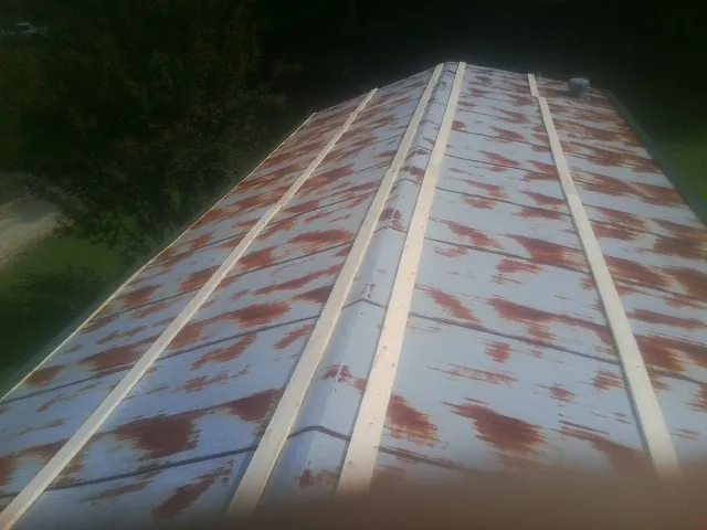 Rusted metal roof panels with new wood purlins before replacement — Storm Damage Roof Repair in Spangler by Roofing Brothers
