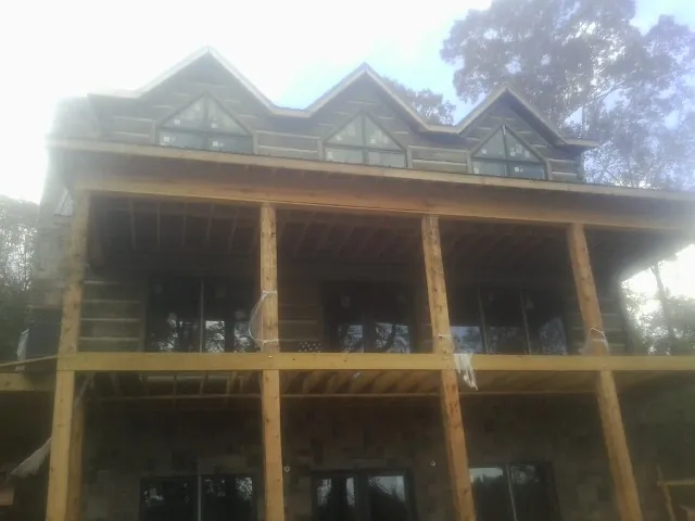 Dormers and porch framing on a large log home under construction — Roof Coating work by our crew in Spangler