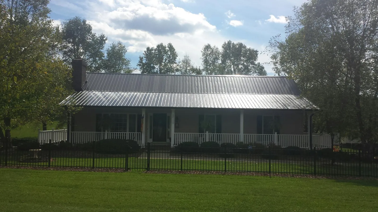 Gray metal roof on a brick ranch with a full width front porch — Gutter Guard Installation work by our crew in Spangler