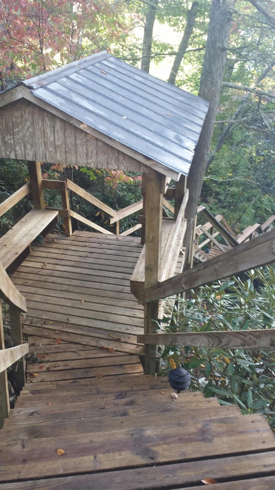Metal roofed shelter over wooden steps on a wooded walkway — Skylight Repair & Installation work by our crew in Spangler
