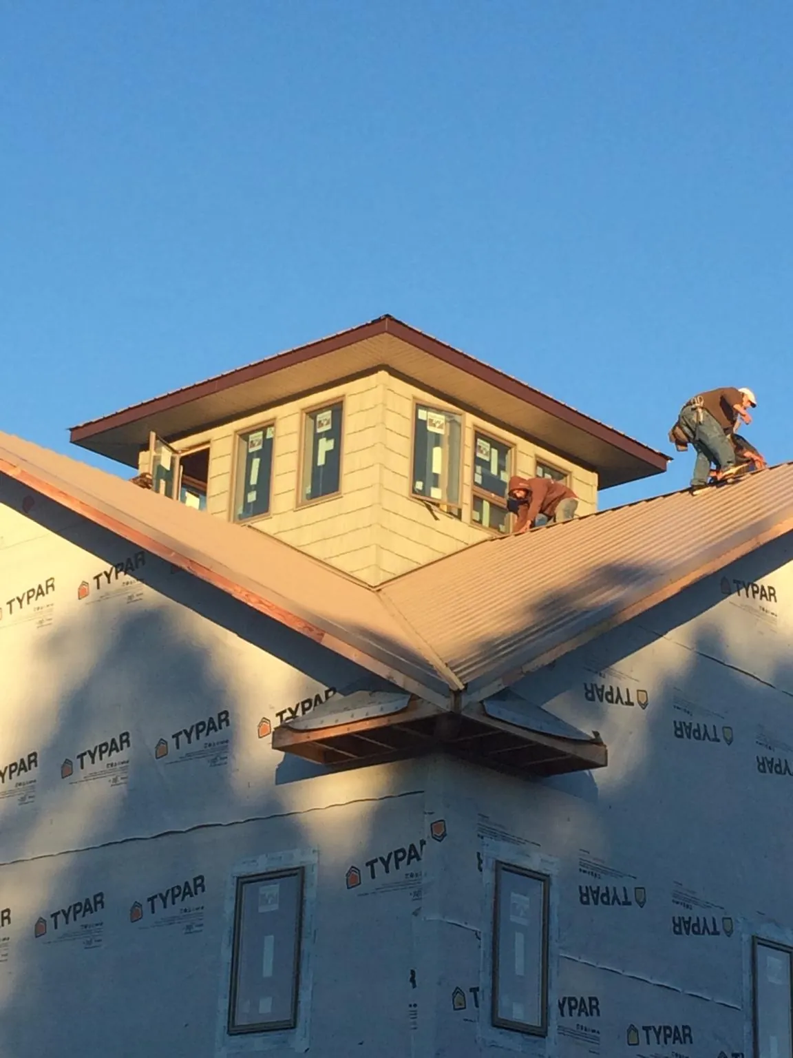 Roofers working around a rooftop cupola on a new metal roof at sunset — Roof Waterproofing in Spangler by Roofing Brothers
